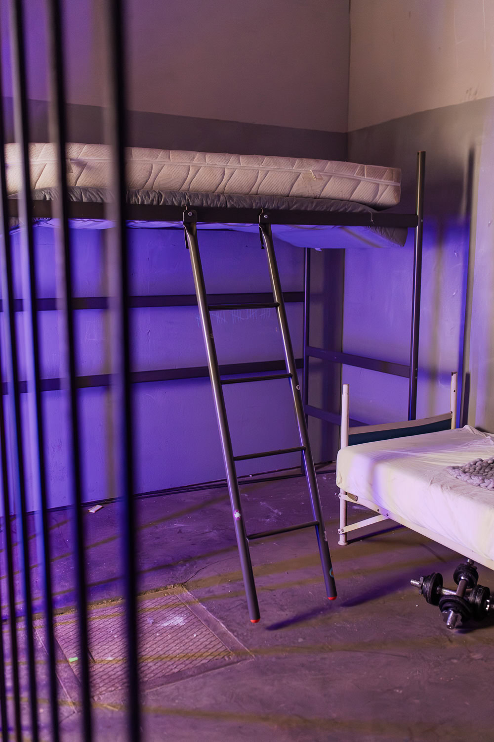 Das Bild zeigt einen modernen Raum mit einem Hochbett und einer Treppe, die zum oberen Schlafbereich führt, beleuchtet in einem sanften lila Licht. In Ingolstadt und Pfaffenhofen wäre dieser geeignete Ort perfekt für interessante Boudoir-Fotografie-Shootings, die kreative Akzente setzen.